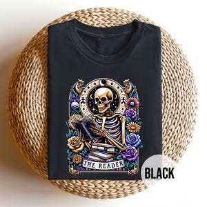 May include: Black t-shirt with a graphic of a skeleton reading a book surrounded by flowers. The text "The Reader" is below the skeleton.