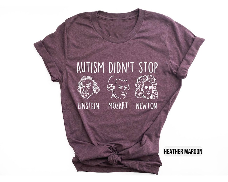 Pu&ograve; includere: T-shirt color marrone rossiccio con testo bianco che recita "L'autismo non si &egrave; fermato" e presenta illustrazioni di Albert Einstein, Mozart e Isaac Newton. Il testo sotto le illustrazioni recita "Einstein, Mozart, Newton."