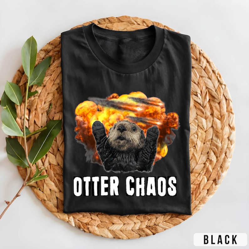May include: Black t-shirt with a graphic of an otter in a fiery explosion. The text "Otter Chaos" is printed below the image.