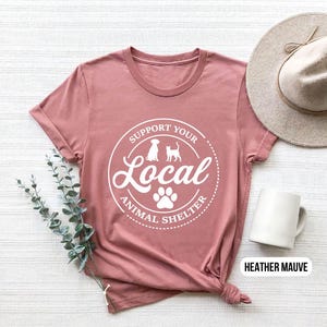 May include: Heather mauve t-shirt with a white graphic that says "Support Your Local Animal Shelter" with a paw print and silhouettes of a dog and cat.