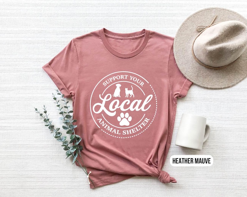 May include: Heather mauve t-shirt with a white graphic that says "Support Your Local Animal Shelter" with a paw print and silhouettes of a dog and cat.