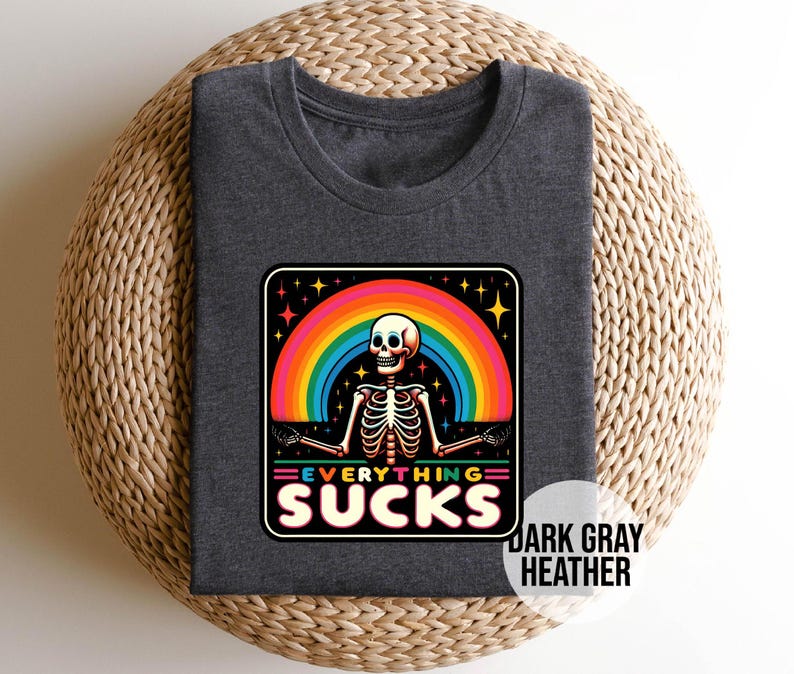 Pu&ograve; includere: T-shirt in grigio scuro melange con una grafica di arcobaleno e scheletro. Il testo "Everything Sucks" &egrave; stampato in un font colorato.