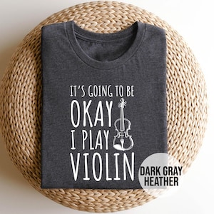 May include: Dark gray heather t-shirt with the text "It's going to be okay I play violin" and a white outline of a violin.