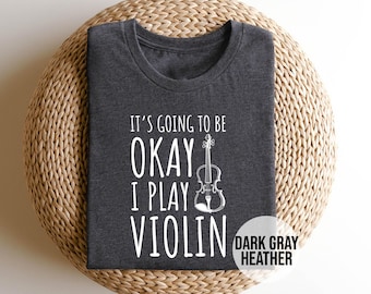May include: Dark gray heather t-shirt with the text "It's going to be okay I play violin" and a white outline of a violin.