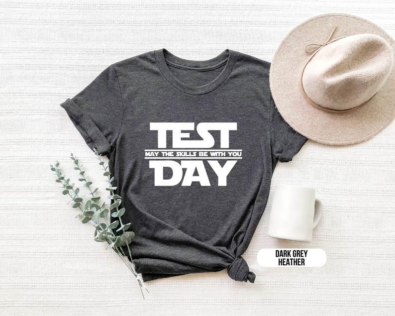 K&ouml;nnte beinhalten: Dunkelgraues T-Shirt mit Melange-Effekt und wei&szlig;em Text, der "TEST MAY THE SKILLS BE WITH YOU DAY" lautet.