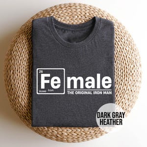 May include: Dark gray heather t-shirt with a white graphic of a periodic table element. The element is labeled "Fe" for iron and "Female" with the text "The Original Iron Man".