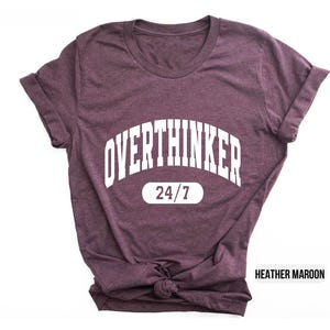 Peut inclure: T-shirt en marron chin&eacute; avec un texte blanc qui dit "Overthinker 24/7".