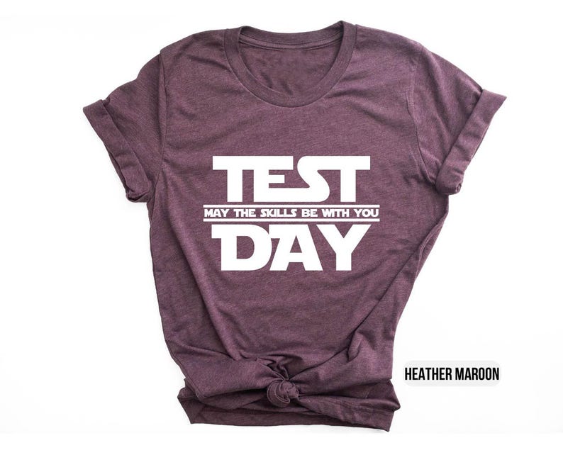 K&ouml;nnte beinhalten: T-Shirt in Heidekraut-Maroon mit wei&szlig;em Text, der "TEST MAY THE SKILLS BE WITH YOU DAY" lautet.