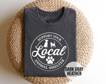 May include: Dark gray heather t-shirt with a white circle graphic that says "Support Your Local Animal Shelter" with a paw print and silhouettes of a dog and cat.