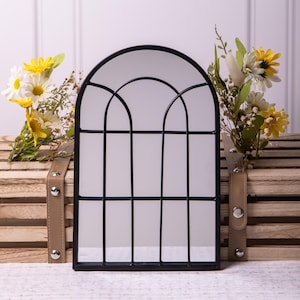 Puede incluir: Espejo arqueado negro con un patrón de rejilla. El espejo está enmarcado en metal negro y tiene una forma rectangular.