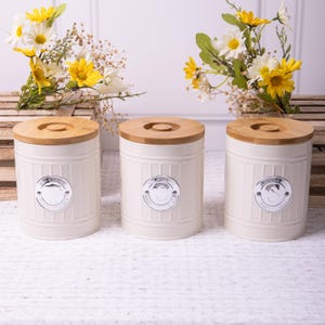 May include: Three white ceramic canisters with bamboo lids. Each canister has a silver label with a stylised image of a sheep and the text "The Sheep Shed".