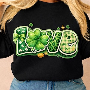 Peut inclure: Sweat-shirt noir avec le mot "LOVE" en vert, orné d'un motif de trèfle et de trèfle à quatre feuilles. Le "L" a un nœud, le "O" est un trèfle à quatre feuilles, le "V" a un imprimé léopard et le "E" a un motif à carreaux.