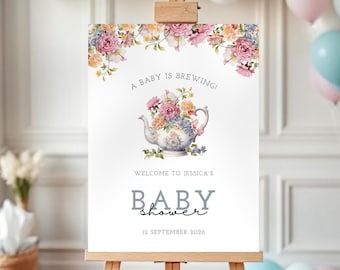 Può includere: Un cartello rettangolare bianco su un cavalletto di legno con un'illustrazione di una teiera floreale e il testo A BABY IS BREWING! WELCOME TO JESSICA'S BABY shower 12 SEPTEMBER 2026. Il bordo superiore è decorato con fiori rosa, gialli, blu e foglie.
