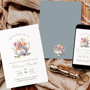 Op de afbeelding: Uitnodigingen voor een bruidsdouche en een smartphone met hetzelfde ontwerp. De uitnodigingen tonen een bloemen theepot illustratie en de tekst "Time for tea with the bride-to-be" en details voor Olivia's feest. Een gouden zegel is ook zichtbaar.