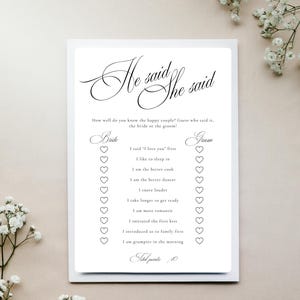 Puede incluir: Una tarjeta de juego de boda rectangular blanca titulada He said She said en elegante letra negra. La tarjeta presenta una lista de afirmaciones con casillas de verificaci&oacute;n en forma de coraz&oacute;n para Bride y Groom, incluyendo I said I love you first.