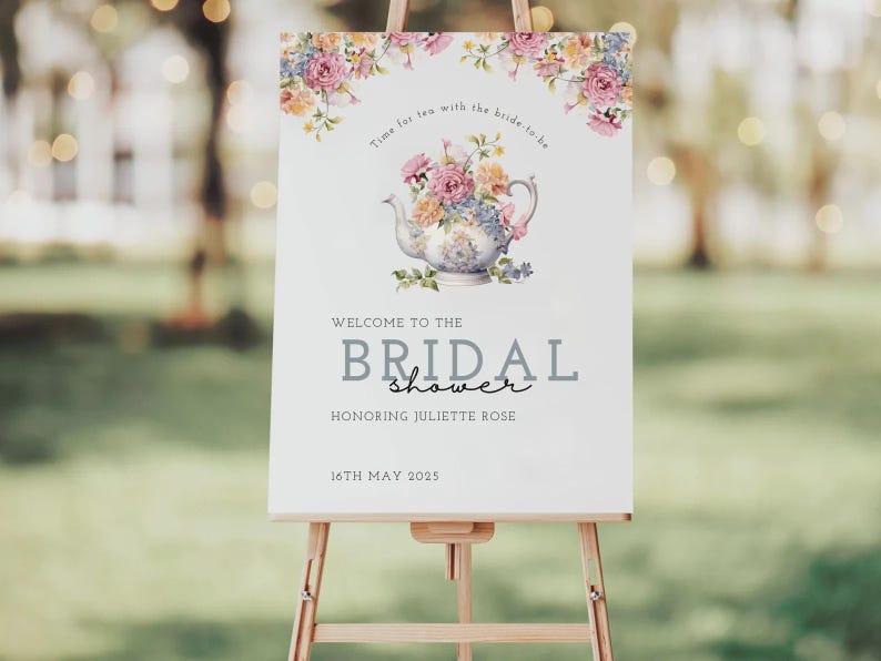 Op de afbeelding: Een wit bord op een ezel met bloemversieringen en de tekst "Welkom bij de Bridal Shower" en "Ter ere van Juliette Rose". Een theepotillustratie is gecentreerd boven de tekst. De datum "16 mei 2025" staat onderaan.