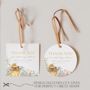 May include: Two white gift tags with brown leather string. One is square, the other is round. Both have gold text that reads "THANK YOU" and "Ashley's Bridal Shower 18.04.2025". Floral and honey jar illustrations decorate the tags.