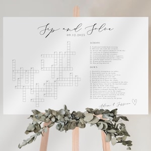 May include: A white crossword puzzle sign with the words "Tip and Solve" and the date 09.12.2025 in elegant script. The puzzle includes clues and is displayed on a wooden easel, decorated with greenery.