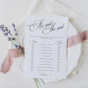 Puede incluir: Una tarjeta de juego rectangular blanca con bordes irregulares que presenta el texto negro He said She said y una lista de preguntas con casillas de verificaci&oacute;n en forma de coraz&oacute;n. La tarjeta est&aacute; sobre un plato blanco con lavanda y cinta rosa.