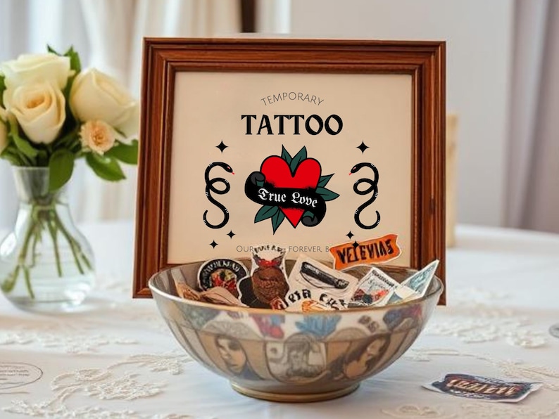 K&ouml;nnte beinhalten: Ein gerahmtes Schild mit dem Text "Temporary Tattoo" und einem Herzen mit den Worten "True Love" darin. Das Schild steht auf einem Tisch mit einer Sch&uuml;ssel voller tempor&auml;rer Tattoos.