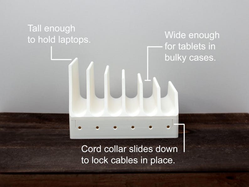 May include: White plastic stand with six slots for holding devices like laptops and tablets. The stand has a cord collar that slides down to lock cables in place. "Tall enough to hold laptops. Wide enough for tablets in bulky cases. Cord collar slides down to lock cables in place."
