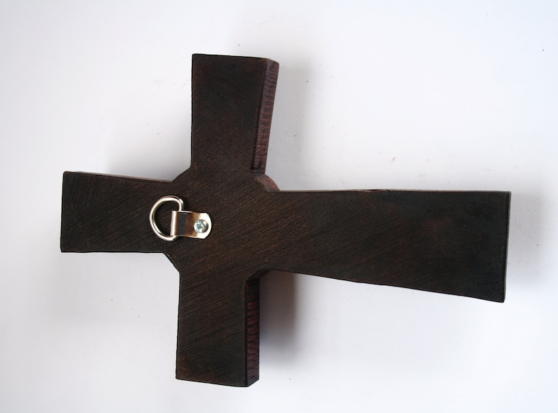 Pu&ograve; includere: Una croce di legno marrone scuro con un gancio di metallo per appendere sul retro.