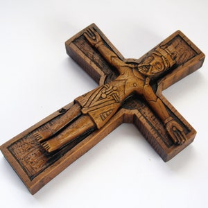 Pu&ograve; includere: Un crocifisso in legno con una scultura dettagliata di Ges&ugrave; Cristo. La croce &egrave; marrone e ha una superficie testurizzata.