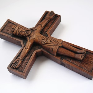 Pu&ograve; includere: Un crocifisso in legno con una scultura dettagliata di Ges&ugrave; Cristo. La croce &egrave; di colore marrone scuro e ha una superficie testurizzata.