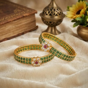 Può includere: Due bracciali rigidi dorati con cerniera caratterizzati da un motivo a griglia di pietre verdi quadrate. Ogni bracciale è impreziosito da un motivo floreale centrale composto da pietre bianche trasparenti attorno a una pietra rossa rotonda.