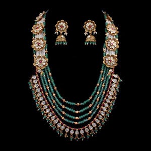 K&ouml;nnte beinhalten: Ein aufwendiges Halsketten- und Ohrring-Set. Die Halskette hat mehrere Str&auml;nge aus gr&uuml;nen Perlen, goldfarbene Details und florale Anh&auml;nger mit roten und wei&szlig;en Steinen. Die Ohrringe haben ein passendes florales Design mit gr&uuml;nen glockenf&ouml;rmigen Anh&auml;ngern.
