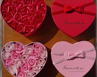 May include: Four heart-shaped boxes. Two are filled with rose-shaped soaps, one red and one pink. The other two are closed, one red with a bow and the text "Forever with you", and one pink with a bow and the same text.