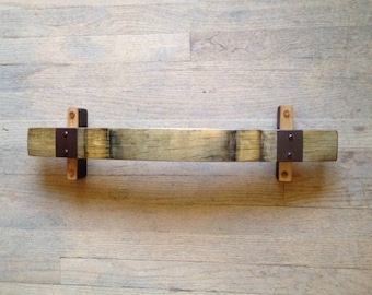 May include: A wooden shelf made from a reclaimed wine barrel stave with metal brackets. The shelf is approximately 18 inches long and 2 inches wide.