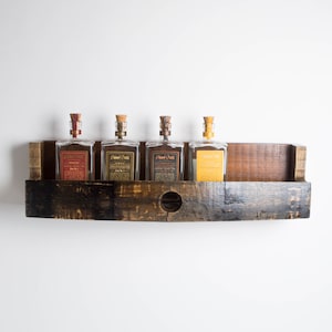 May include: A dark brown wooden shelf with a curved front edge. The shelf has a circular hole in the center and is holding four glass bottles with cork tops. The bottles are labeled 