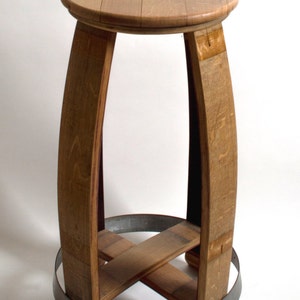 Puede incluir: Un taburete de madera hecho de un barril de vino reutilizado. El taburete tiene un asiento redondo y una base de metal.