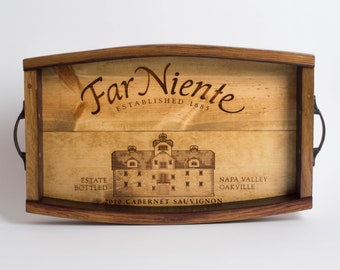May include: Wooden serving tray with the words "Far Niente" and "Established 1885" engraved on the surface. The tray also features an illustration of a building and the text "Estate Bottled", "Napa Valley Oakville", and "2010 Cabernet Sauvignon".