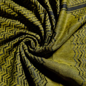 以下が含まれることがあります： オリーブグリーンと黒の織物。 繰り返し模様の幾何学模様が特徴です。 生地は折りたたまれ、質感とデザインが際立っています。 ジグザグと線の連続模様で、立体感のある効果を生み出しています。