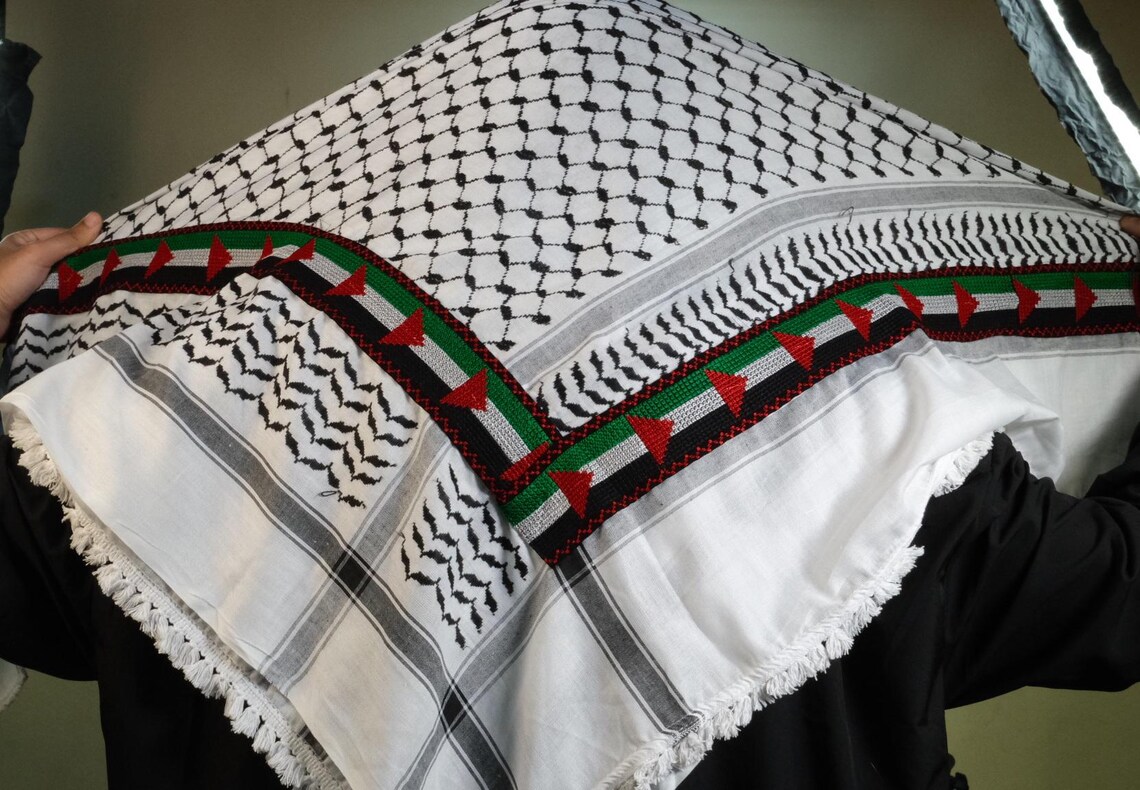 كوفية فلسطينية بيضاء وسوداء مطوية بنقشة هندسية تقليدية وتفاصيل شرّابات (5)