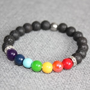 May include: A beaded bracelet featuring a combination of black lava rock beads and colorful chakra beads. The chakra beads are arranged in a rainbow sequence, with a silver bead and silver accents.