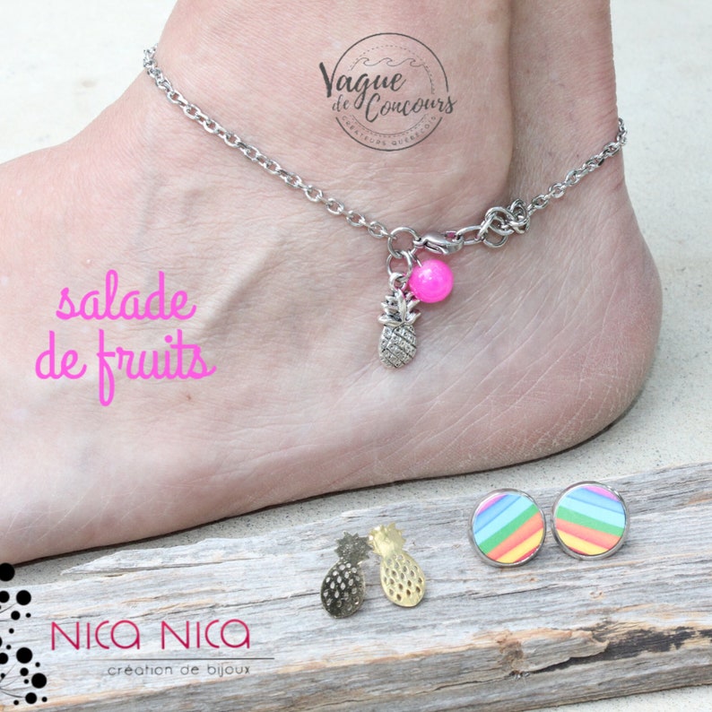 Pu&ograve; includere: Una cavigliera argentata con un ciondolo a forma di ananas e una perla rosa. L'immagine mostra anche un paio di orecchini a bottone a righe arcobaleno e due orecchini a forma di ananas. Il testo "salade de fruits" &egrave; visibile.