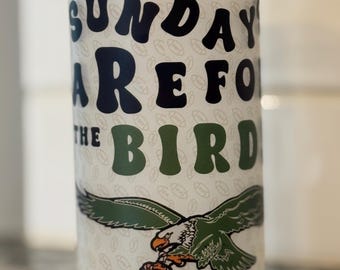 May include: White glass jar with a bamboo lid. The jar has a green and black graphic of an eagle with the text "Sundays are for the Birds" printed on it.
