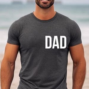 May include: A dark gray t-shirt with the word "DAD" printed in white on the front.