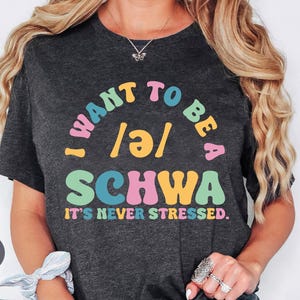 May include: Heather dark gray t-shirt with the text "I want to be a /ə/ SCHWA it's never stressed."