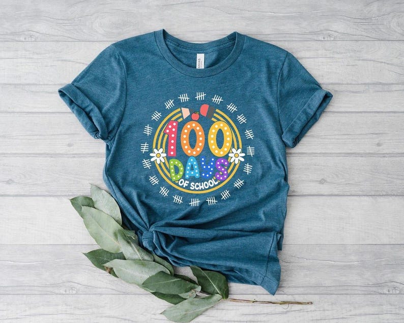 Pu&ograve; includere: Una maglietta blu turchese con una grafica colorata che dice "100 giorni di scuola" circondata da un cerchio di segni di hash e fiori.