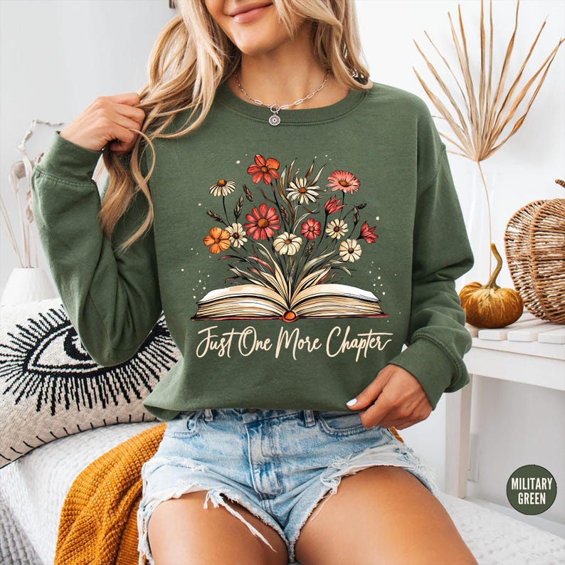 May include: A green sweatshirt with a floral design and an open book with the text "Just One More Chapter".
