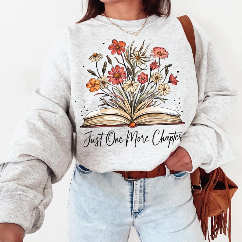 May include: A gray sweatshirt with a floral design and an open book with the text "Just One More Chapter".