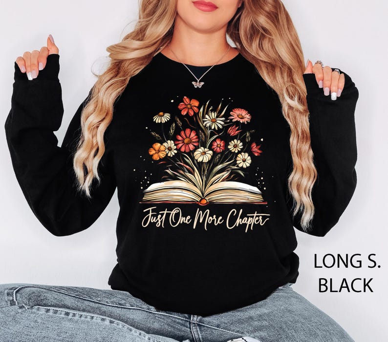 May include: Black long-sleeved sweatshirt with a graphic of an open book with flowers growing out of it. The text "Just One More Chapter" is printed below the book.