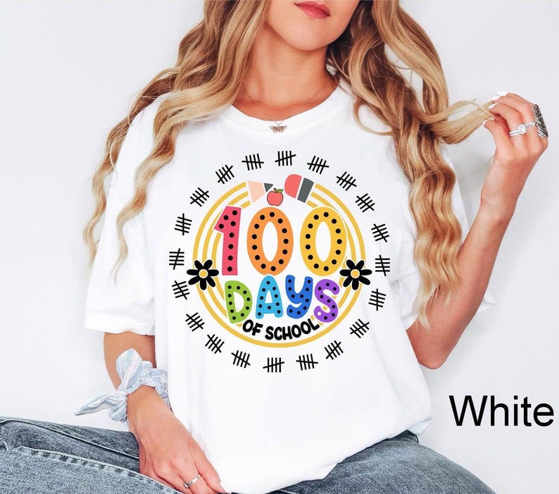Pu&ograve; includere: Maglietta bianca con una grafica colorata che dice "100 giorni di scuola" circondata da un cerchio di segni di hash neri e un bordo arcobaleno.