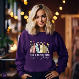 May include: A purple sweatshirt with the text "THERE IS NO SUCH THING as too many books" and a graphic of colorful books and flowers. The sweatshirt is a solid purple color.