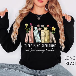 May include: Black long-sleeve sweatshirt with the text "THERE IS NO SUCH THING as too many books." The design features a stack of books with colorful flowers. The sweatshirt is labeled "LONG S. BLACK."