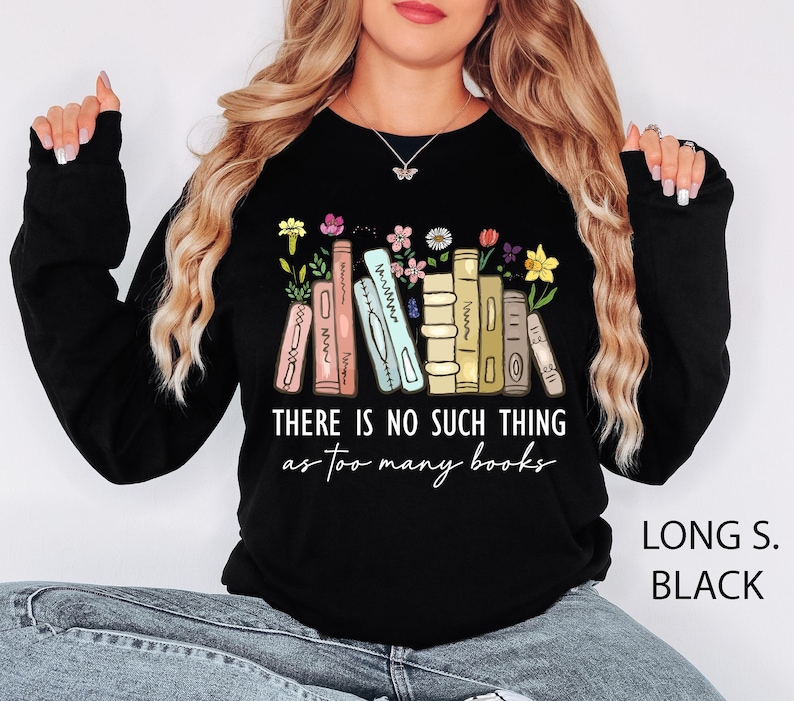 May include: Black long-sleeve sweatshirt with the text "THERE IS NO SUCH THING as too many books." The design features a stack of books with colorful flowers. The sweatshirt is labeled "LONG S. BLACK."